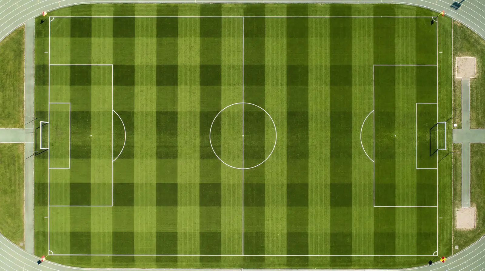 Vue aérienne d'un terrain de football avec pelouse rayée et lignes blanches avant un match international
